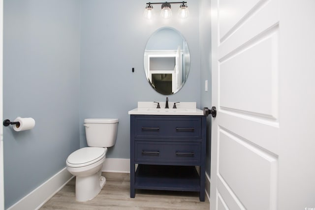 bathroom featuring toilet, baseboards, wood finished floors, and vanity