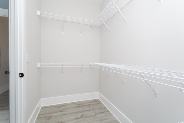 walk in closet with wood finished floors