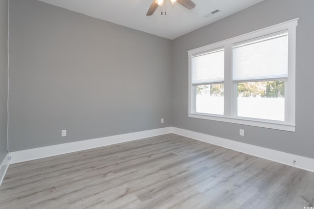 spare room with ceiling fan, light wood-type flooring, visible vents, and baseboards