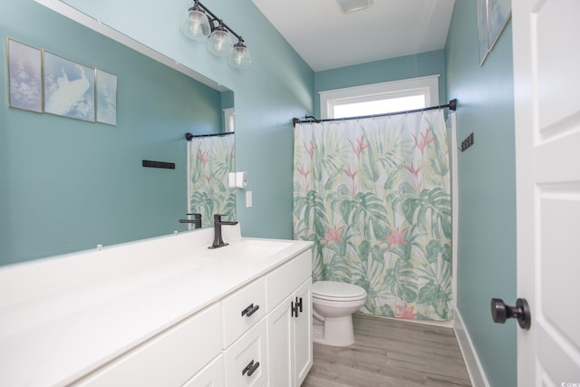 bathroom featuring baseboards, vanity, toilet, and wood finished floors