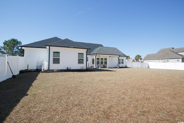 back of property featuring roof with shingles, a lawn, and a fenced backyard