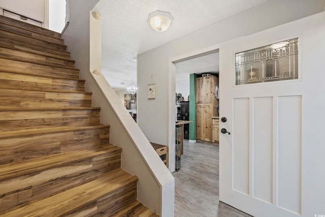 staircase featuring hardwood / wood-style floors and a textured ceiling