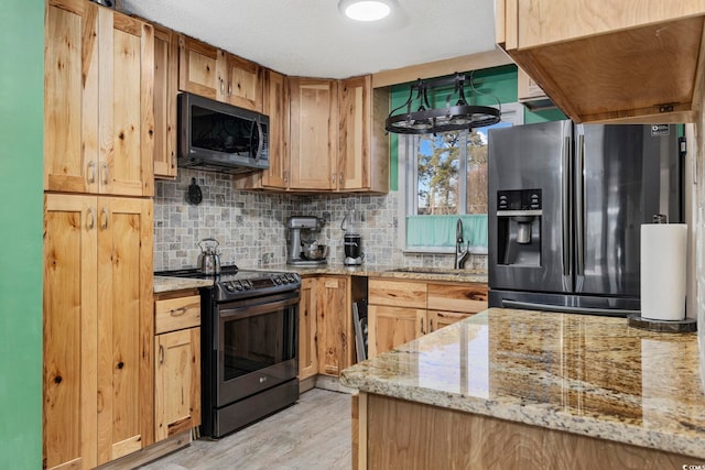 kitchen with sink, light hardwood / wood-style flooring, stainless steel appliances, light stone countertops, and decorative backsplash