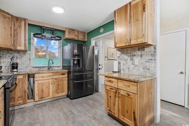 kitchen featuring stainless steel refrigerator with ice dispenser, light hardwood / wood-style flooring, light stone counters, and electric range