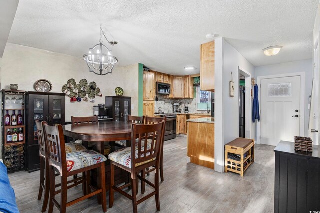 dining space with hardwood / wood-style flooring, a chandelier, and a textured ceiling