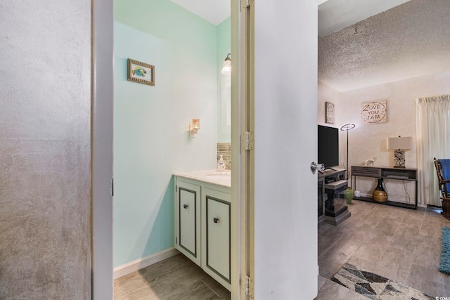 bathroom with vanity, wood-type flooring, and a textured ceiling