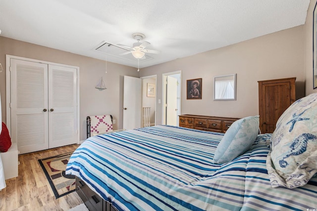 bedroom with ceiling fan, a textured ceiling, light hardwood / wood-style floors, and a closet