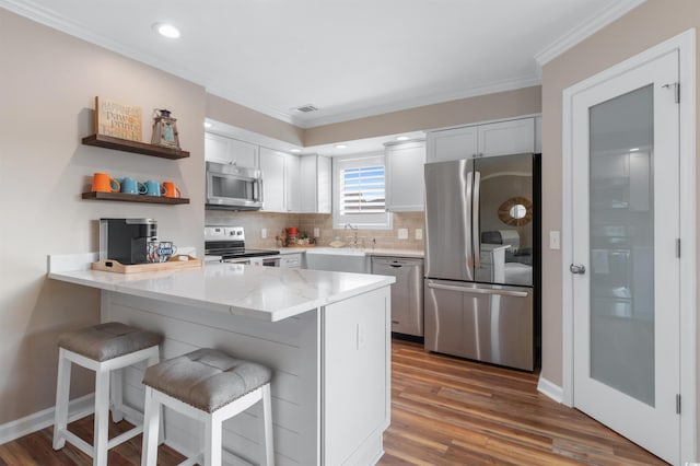 kitchen featuring stainless steel appliances, white cabinetry, a breakfast bar area, and kitchen peninsula