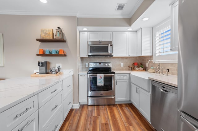 kitchen with dark hardwood / wood-style floors, tasteful backsplash, white cabinets, stainless steel appliances, and crown molding