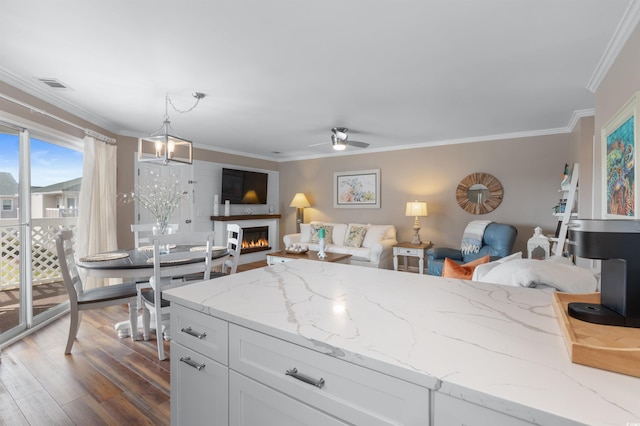 kitchen with pendant lighting, dark hardwood / wood-style flooring, crown molding, and white cabinets