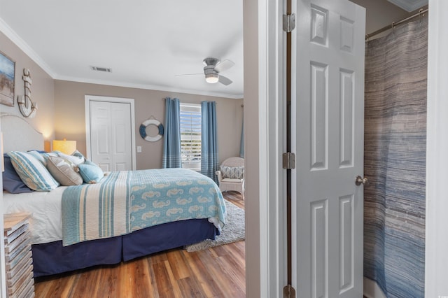 bedroom with ceiling fan, ornamental molding, a closet, and wood-type flooring