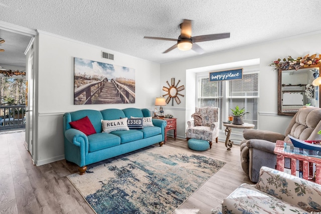 living room with ceiling fan, a textured ceiling, and light hardwood / wood-style floors