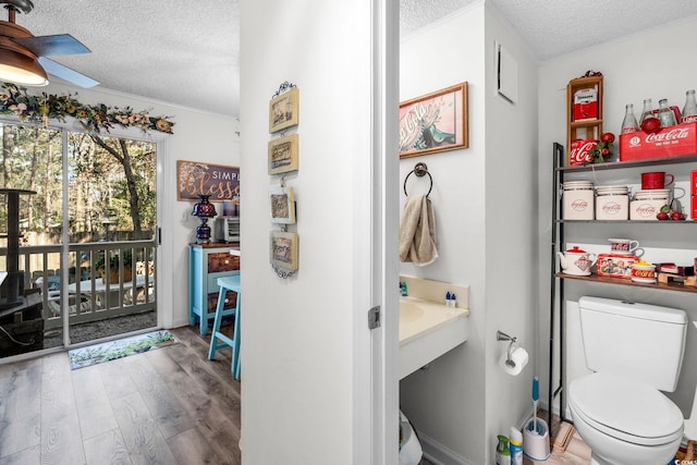 bathroom featuring ceiling fan, wood-type flooring, toilet, and a textured ceiling