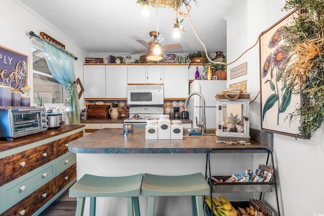 kitchen featuring white cabinetry, white appliances, a breakfast bar, and a textured ceiling