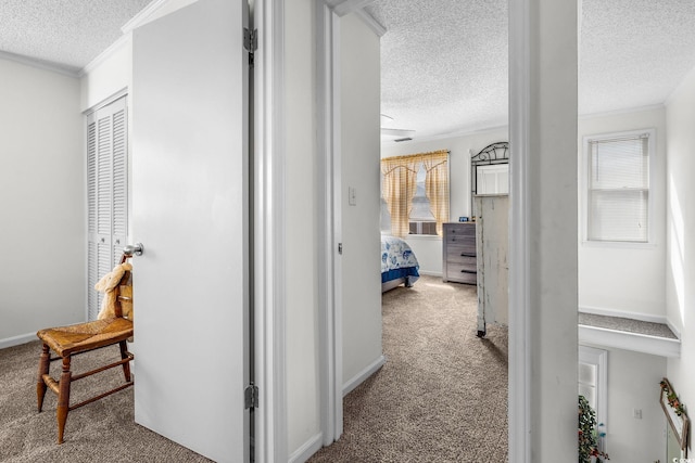 hallway with ornamental molding, carpet flooring, and a textured ceiling