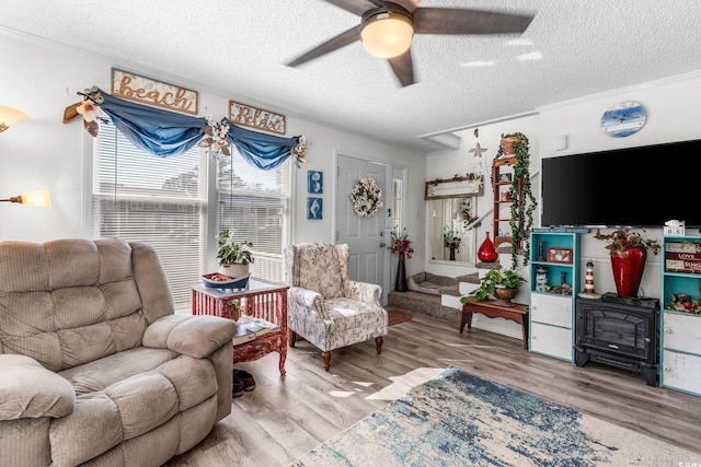 sitting room with light hardwood / wood-style flooring, a textured ceiling, and a wood stove