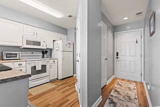 kitchen with a toaster, light wood finished floors, white cabinetry, white appliances, and baseboards