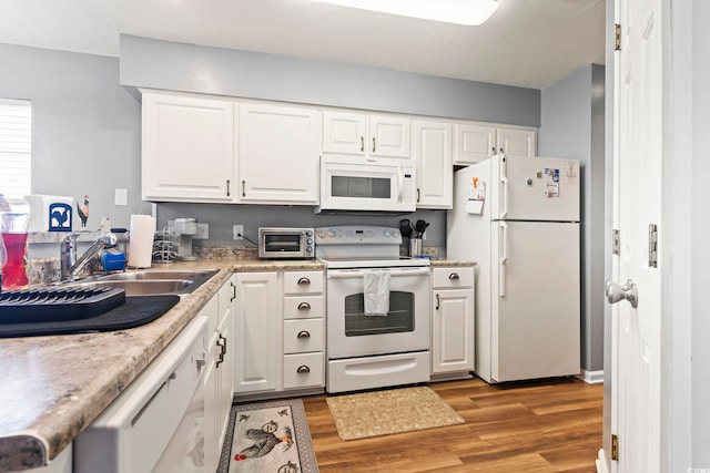 kitchen with white appliances, a toaster, light countertops, light wood-type flooring, and white cabinetry