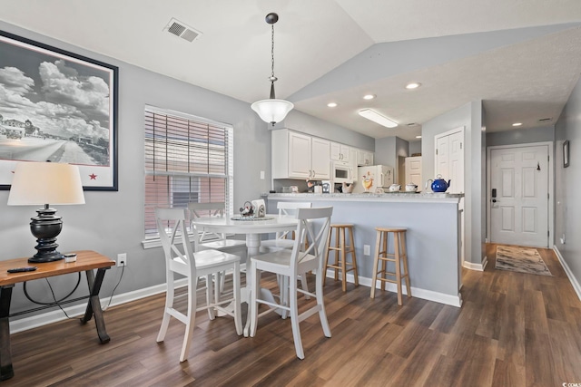 dining space with lofted ceiling and dark hardwood / wood-style floors