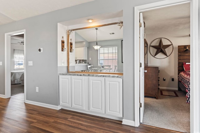 kitchen featuring vaulted ceiling, dark hardwood / wood-style floors, pendant lighting, ceiling fan, and white cabinets