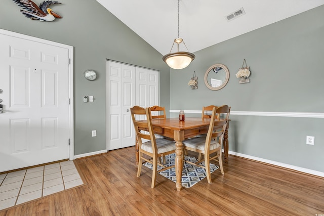 dining room with high vaulted ceiling and light wood-type flooring