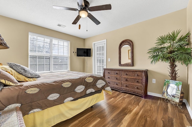 bedroom featuring ceiling fan, dark wood-type flooring, access to outside, and a textured ceiling