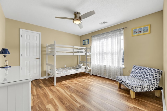 bedroom featuring ceiling fan, hardwood / wood-style flooring, and a textured ceiling