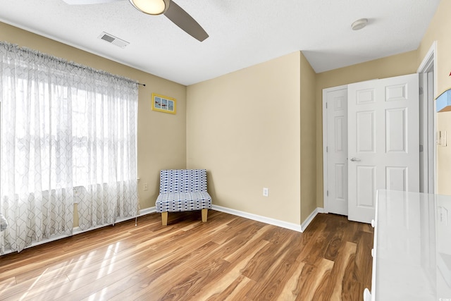 unfurnished room with hardwood / wood-style flooring, ceiling fan, and a textured ceiling