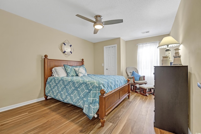 bedroom with hardwood / wood-style floors, a textured ceiling, and ceiling fan