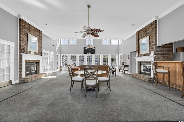 carpeted dining room featuring a towering ceiling, a fireplace, and plenty of natural light