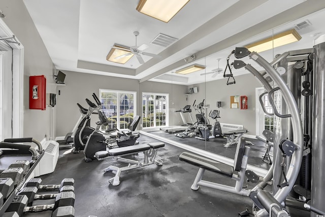 workout area featuring a raised ceiling and ceiling fan