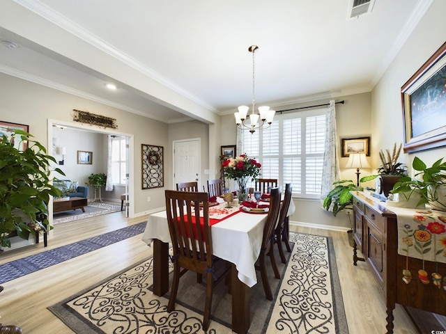 dining area with light wood-style floors, a chandelier, visible vents, and crown molding