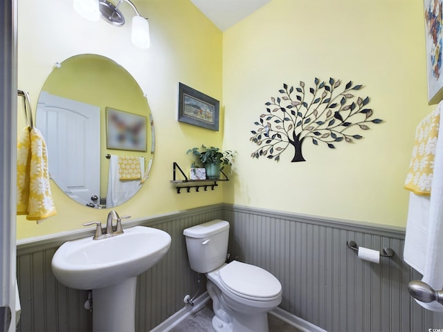 bathroom with a wainscoted wall, a sink, and toilet