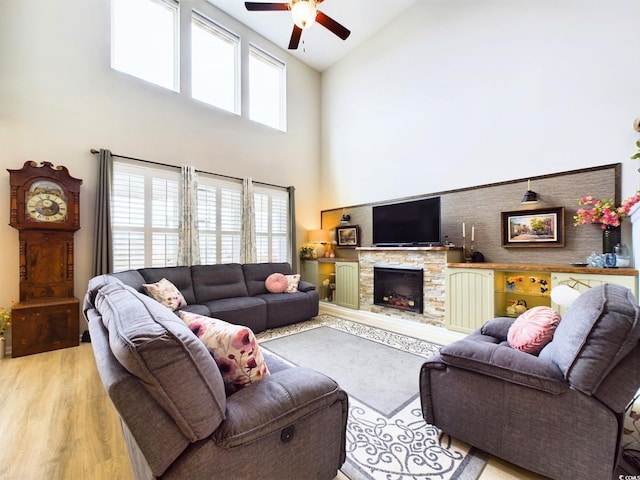 living room with high vaulted ceiling, a fireplace, a ceiling fan, and wood finished floors