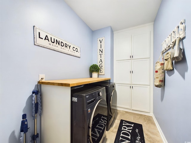 clothes washing area with cabinet space, baseboards, and washer and clothes dryer