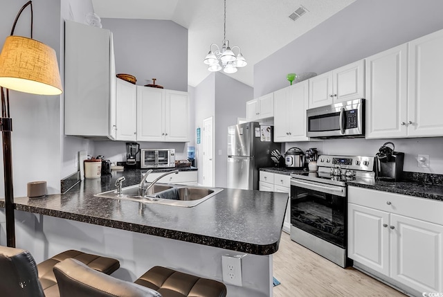 kitchen featuring white cabinetry, decorative light fixtures, and stainless steel appliances