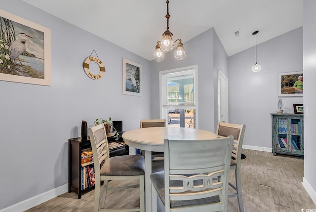 dining room featuring lofted ceiling, a chandelier, and light wood-type flooring