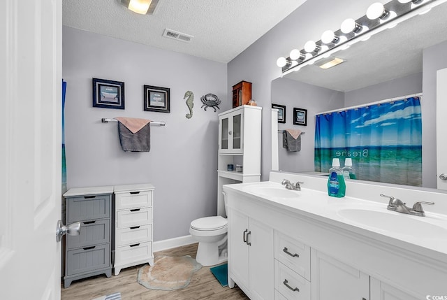 bathroom with vanity, wood-type flooring, toilet, and a textured ceiling