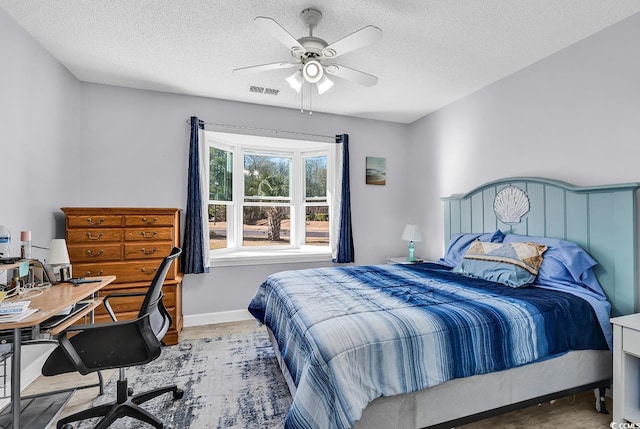 bedroom featuring ceiling fan, hardwood / wood-style floors, and a textured ceiling