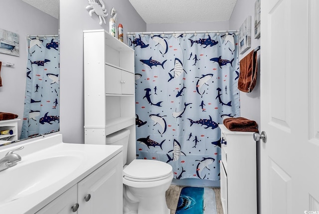 bathroom with vanity, walk in shower, a textured ceiling, and toilet