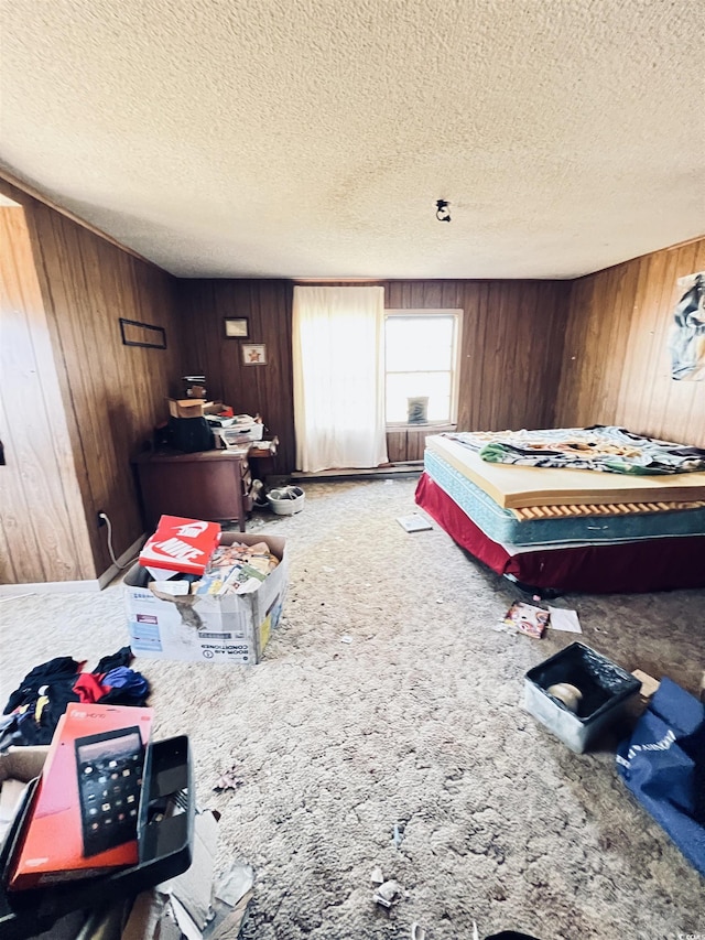 bedroom featuring carpet, a textured ceiling, and wood walls