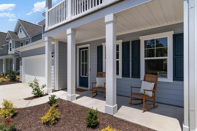 entrance to property with a garage, a balcony, and a porch