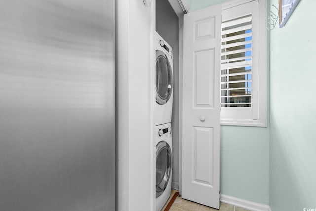 laundry area featuring light tile patterned flooring and stacked washer and clothes dryer