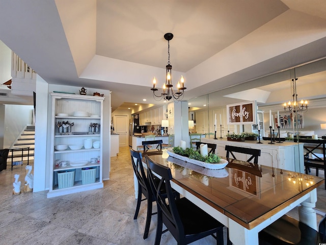 dining area with an inviting chandelier and a tray ceiling