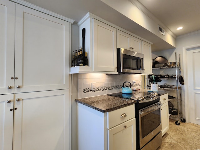 kitchen with crown molding, appliances with stainless steel finishes, white cabinetry, dark stone countertops, and decorative backsplash