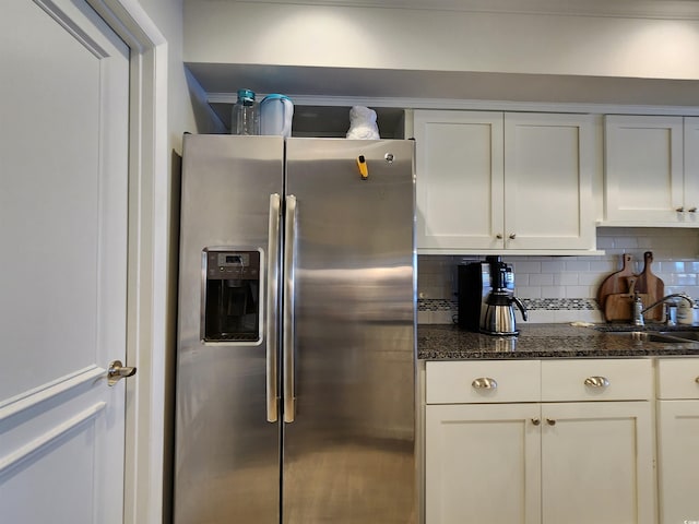 kitchen with dark stone countertops, stainless steel fridge with ice dispenser, tasteful backsplash, and white cabinets