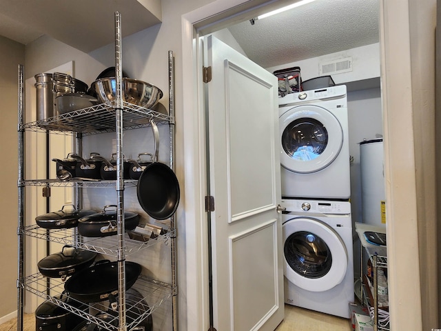 washroom with a textured ceiling and stacked washer / dryer