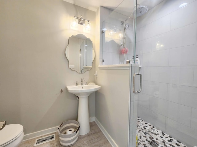 bathroom with walk in shower, toilet, and hardwood / wood-style floors