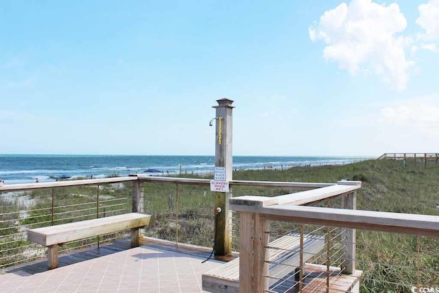 wooden deck featuring a water view and a beach view