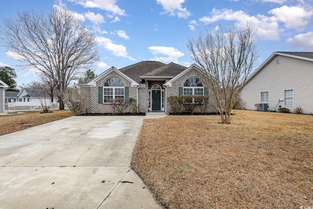 ranch-style house featuring brick siding, fence, concrete driveway, roof with shingles, and a front lawn